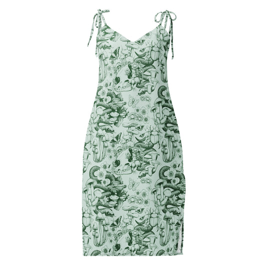 A sleeveless midi-length dress with a V-neckline and self-tie shoulder straps, featuring a detailed sage green ink illustration pattern on a light green background. The moody nature pattern includes human skulls, coiled snakes, beetles, butterflies, and various wild mushrooms and flowers.