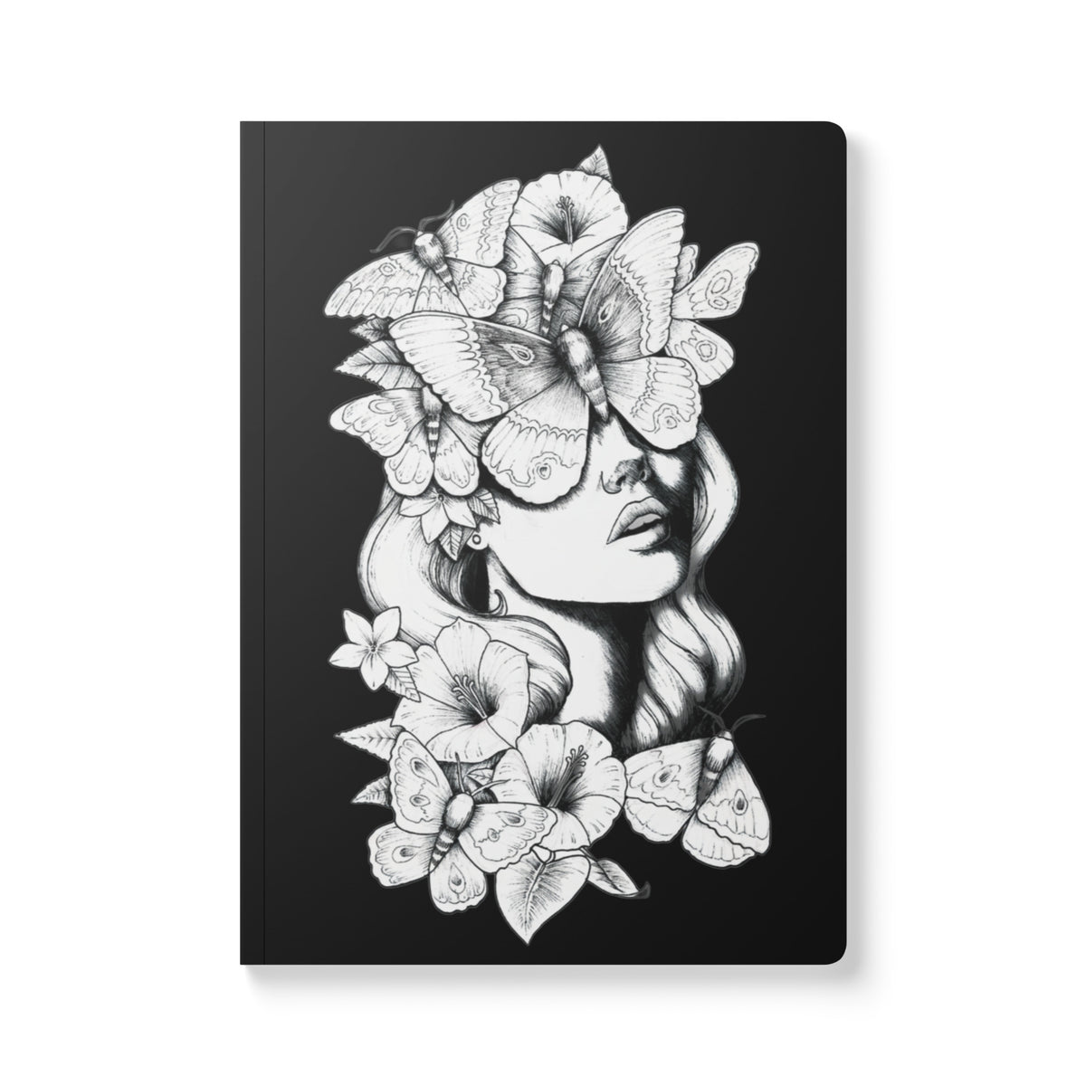 A front-facing view of a rectangular softcover journal with rounded corners, featuring a detailed black and white ink illustration against a solid black background. The design depicts a woman's face surrounded by large moths and blooming hibiscus flowers, with the moths covering her eyes to create a surreal and mystical look.