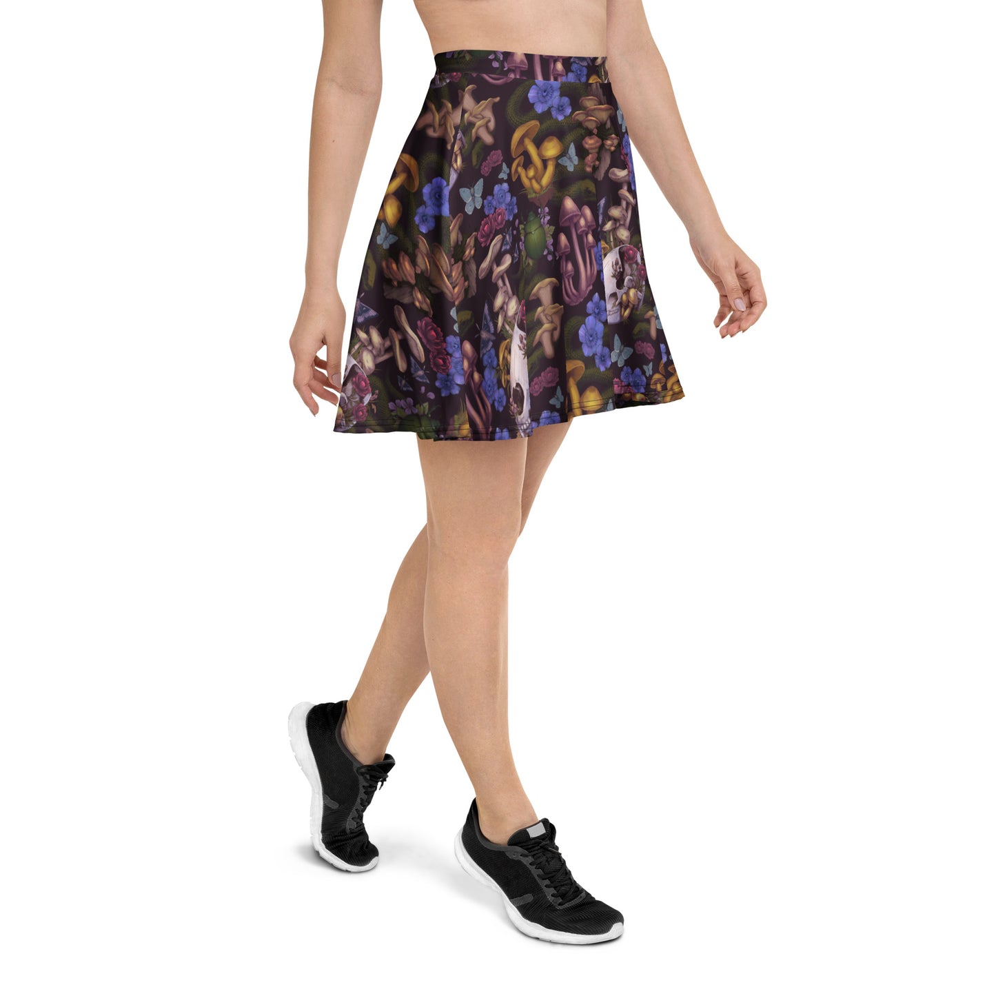 A side-angle view of a person walking, wearing a dark, high-waisted skater skirt featuring a detailed, moody nature print with mushrooms, small skulls, blue butterflies, and dark purple flowers.